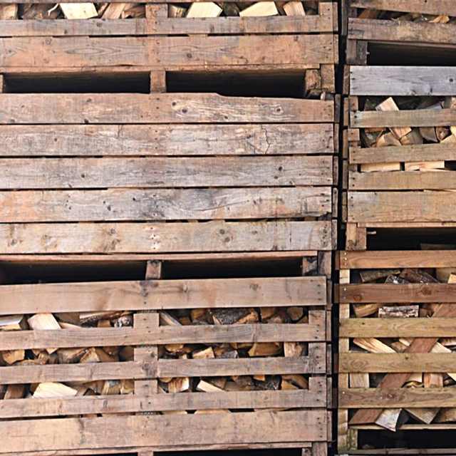 Palettes de bois de chauffage empilées, remplies de bûches sèches calibrées