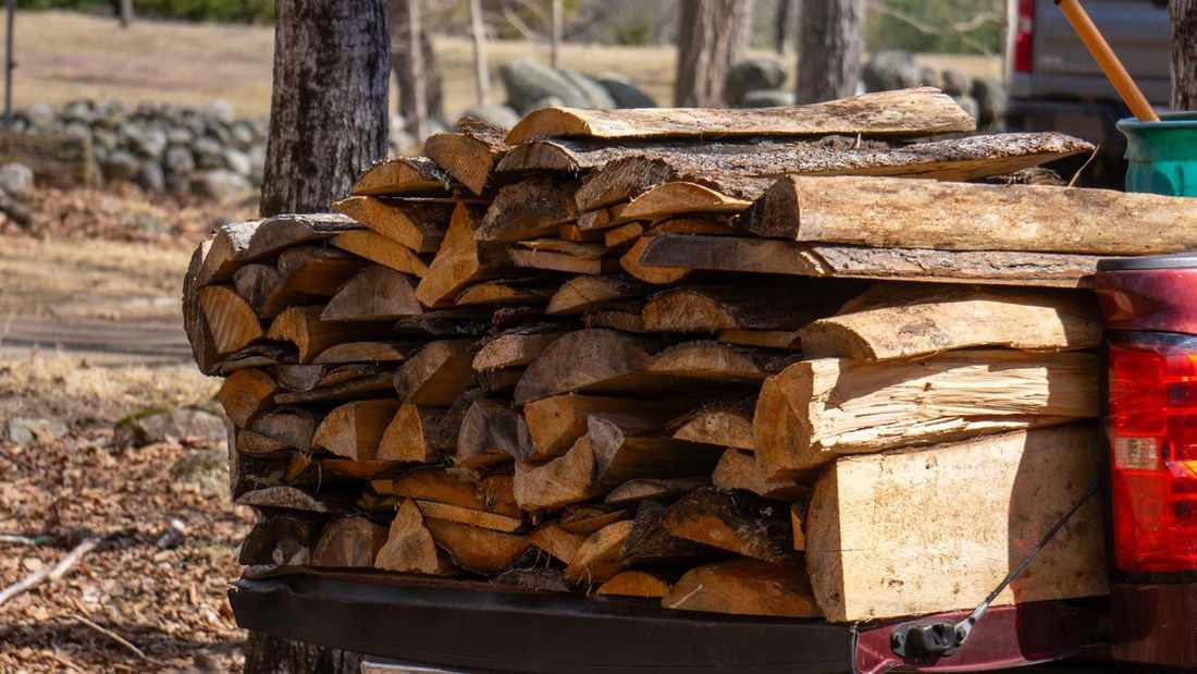 Véhicule utilitaire chargé de bûches de bois sec fendu, prêt pour une livraison